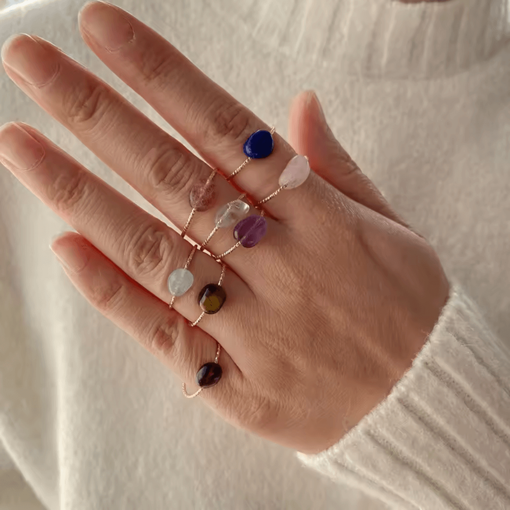 Hand adorned with rough amethyst and rose quartz crystal rings, showcasing nature's beauty and unique crystal formations.